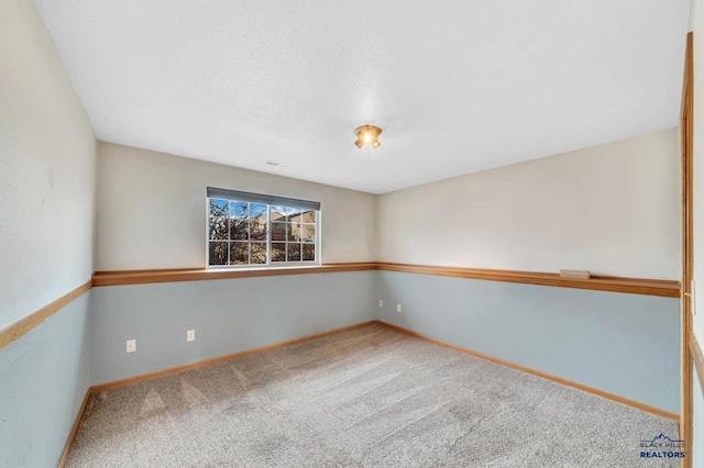 unfurnished room with carpet and a textured ceiling