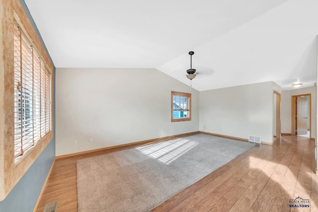 spare room featuring ceiling fan, light hardwood / wood-style floors, and vaulted ceiling