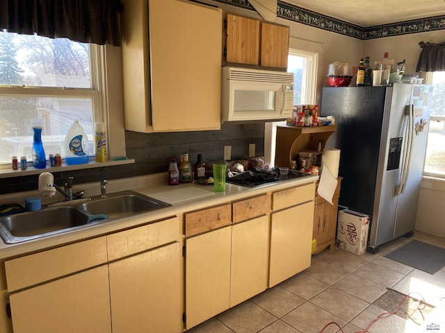 kitchen with sink, stainless steel fridge, black cooktop, and light tile patterned flooring