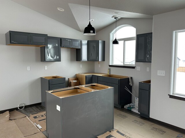 kitchen with a center island, vaulted ceiling, hanging light fixtures, and baseboards