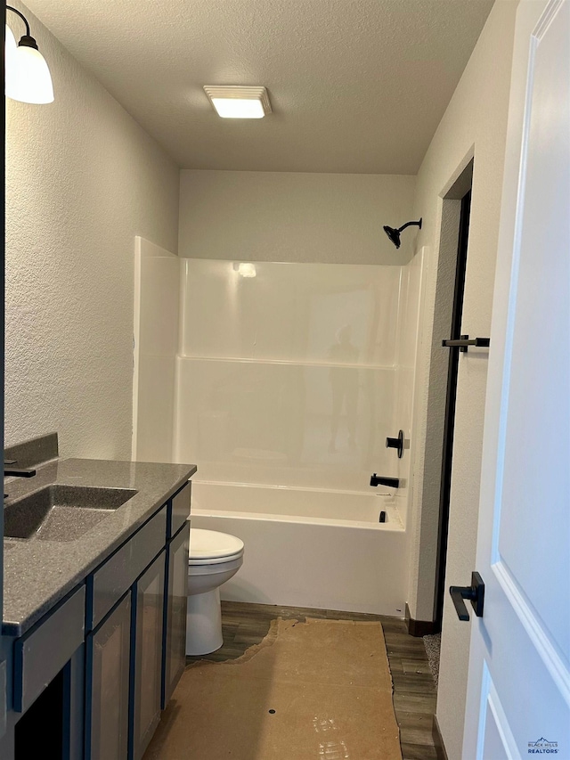 full bath with toilet, a textured ceiling, wood finished floors, and a textured wall