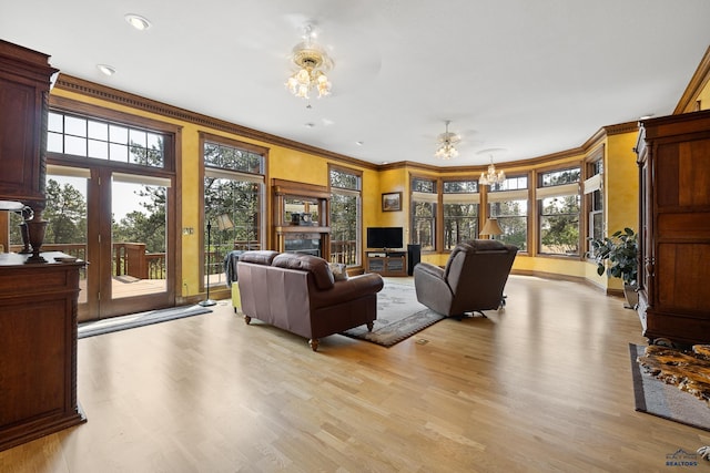 living room featuring ceiling fan, ornamental molding, light hardwood / wood-style floors, and a healthy amount of sunlight