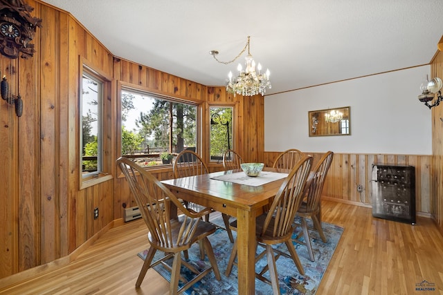 dining room featuring a notable chandelier, light hardwood / wood-style flooring, beverage cooler, and wood walls