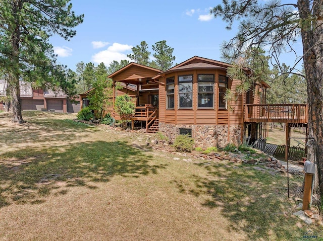 rear view of house featuring a wooden deck and a yard