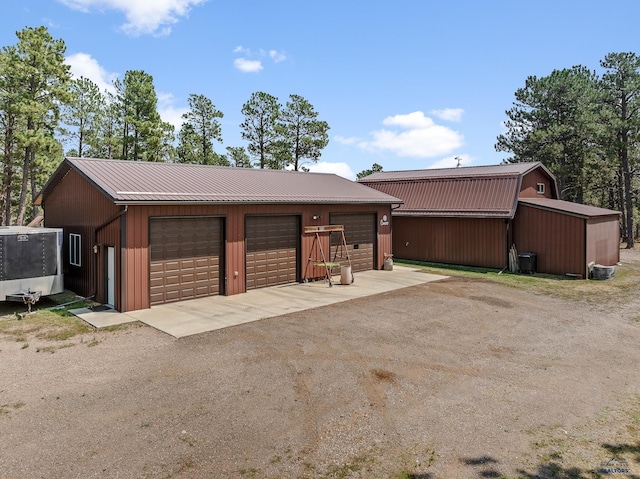 single story home featuring a garage, an outdoor structure, and central air condition unit