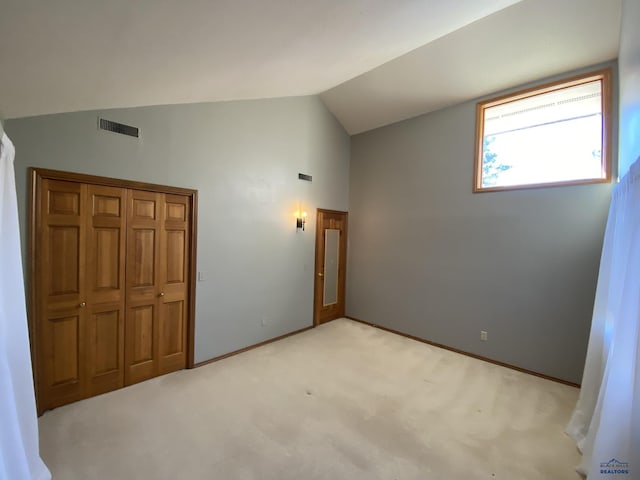 unfurnished bedroom with light carpet, vaulted ceiling, and a closet