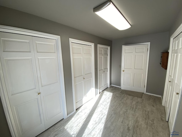 unfurnished bedroom featuring light hardwood / wood-style flooring and two closets