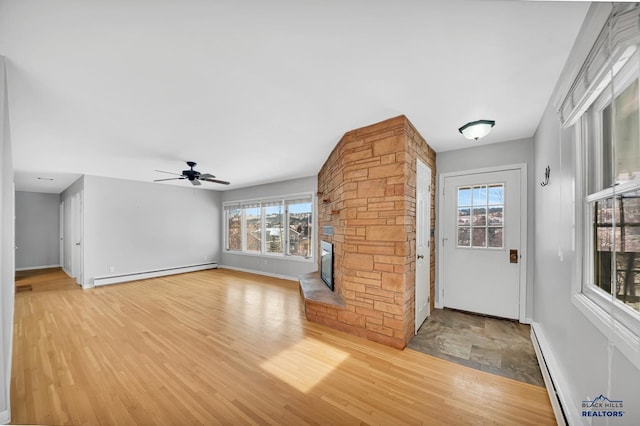 entryway featuring ceiling fan, a fireplace, light hardwood / wood-style floors, and a baseboard heating unit