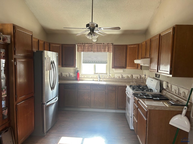 kitchen featuring white range with gas cooktop, sink, stainless steel fridge, and vaulted ceiling