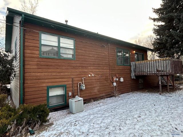 snow covered rear of property featuring a deck and central air condition unit