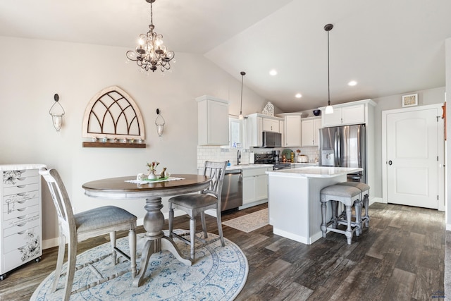 dining space with lofted ceiling, sink, dark hardwood / wood-style floors, and an inviting chandelier