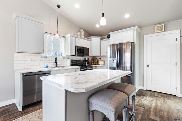 kitchen featuring sink, hanging light fixtures, stainless steel appliances, a center island, and white cabinets