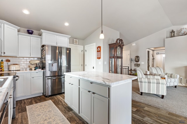 kitchen with white cabinets, a kitchen island, stainless steel fridge, and decorative light fixtures