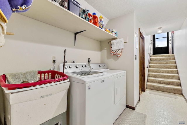 clothes washing area with washing machine and dryer and a textured ceiling