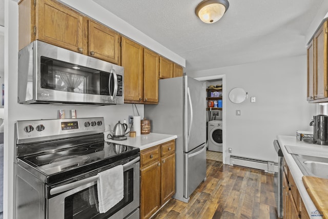 kitchen featuring dark wood-type flooring, washer / dryer, a textured ceiling, appliances with stainless steel finishes, and a baseboard heating unit