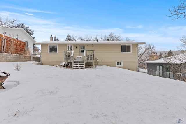 snow covered rear of property with a deck