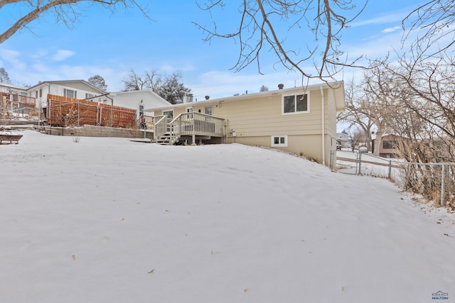 snow covered rear of property featuring a wooden deck