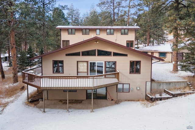 snow covered rear of property with a wooden deck