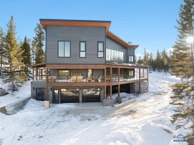 snow covered back of property with a wooden deck