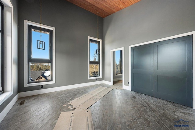 entrance foyer featuring hardwood / wood-style flooring, wooden ceiling, and a towering ceiling