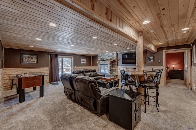 living room with wooden walls, light carpet, a fireplace, and wood ceiling