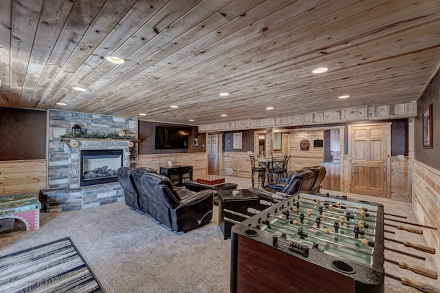living room featuring wood ceiling, wooden walls, carpet floors, and a stone fireplace
