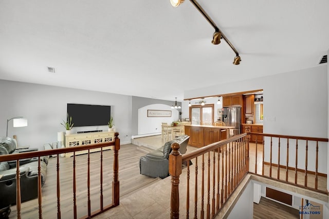 interior space featuring a baseboard radiator, rail lighting, a chandelier, and light hardwood / wood-style flooring