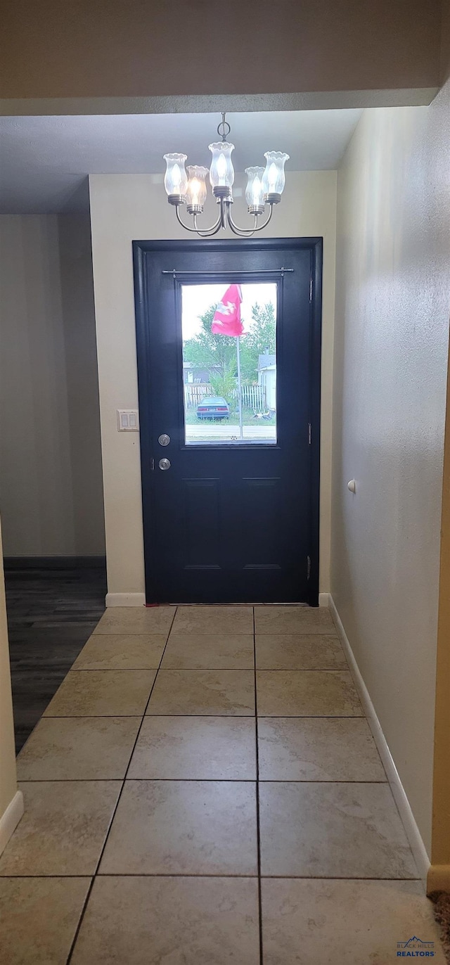 doorway with tile patterned flooring and a notable chandelier