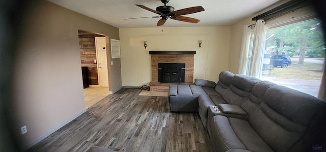 living room featuring a stone fireplace, hardwood / wood-style floors, and ceiling fan