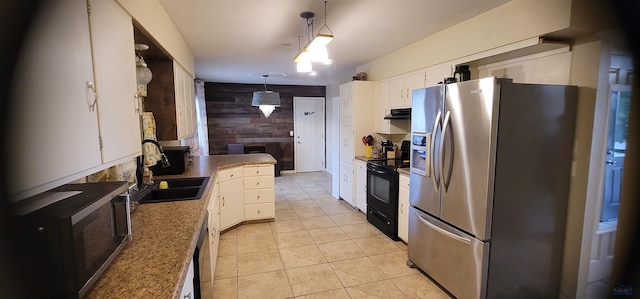 kitchen with hanging light fixtures, wood walls, white cabinets, and appliances with stainless steel finishes