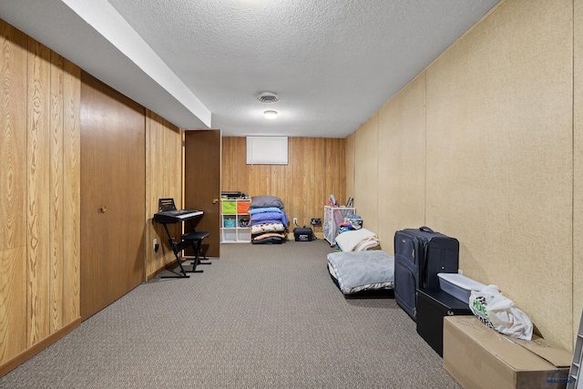 carpeted bedroom featuring a textured ceiling and wood walls