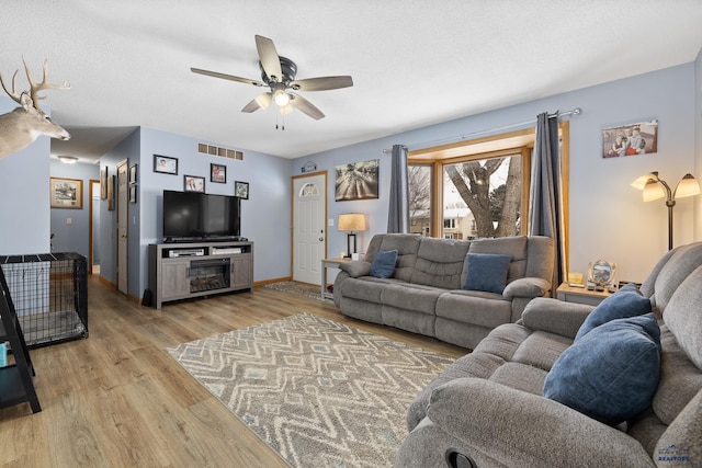 living room featuring ceiling fan, a textured ceiling, and light hardwood / wood-style floors