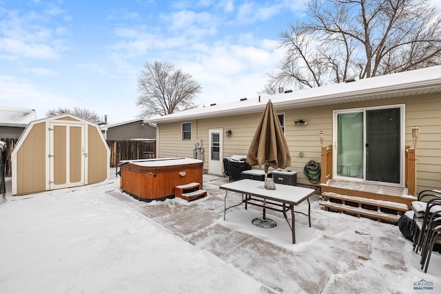 snow covered property with a shed and a hot tub