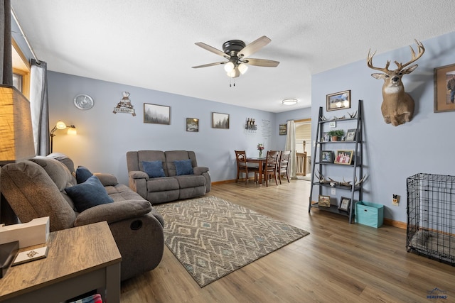 living room with ceiling fan, wood-type flooring, and a textured ceiling