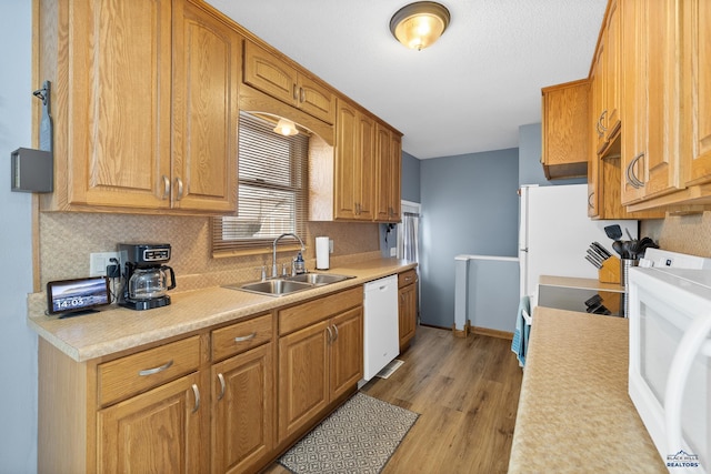 kitchen with sink, decorative backsplash, white appliances, and light wood-type flooring