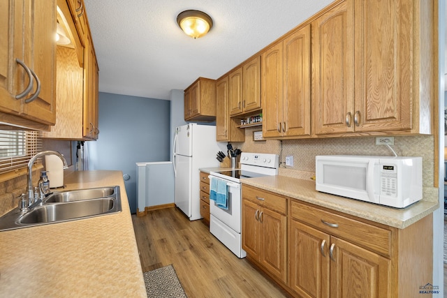 kitchen with sink, tasteful backsplash, a textured ceiling, light wood-type flooring, and white appliances