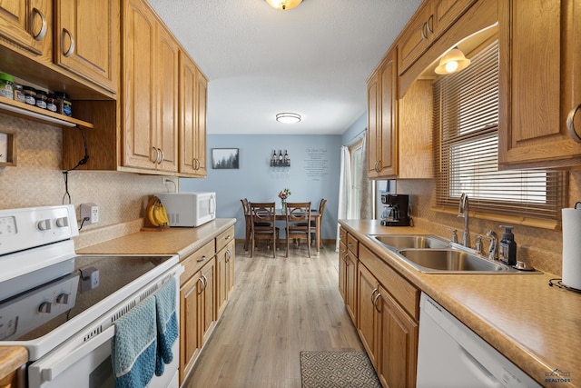 kitchen featuring sink, white appliances, light wood-type flooring, and backsplash