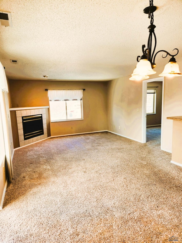 unfurnished living room with carpet flooring, a textured ceiling, and a fireplace