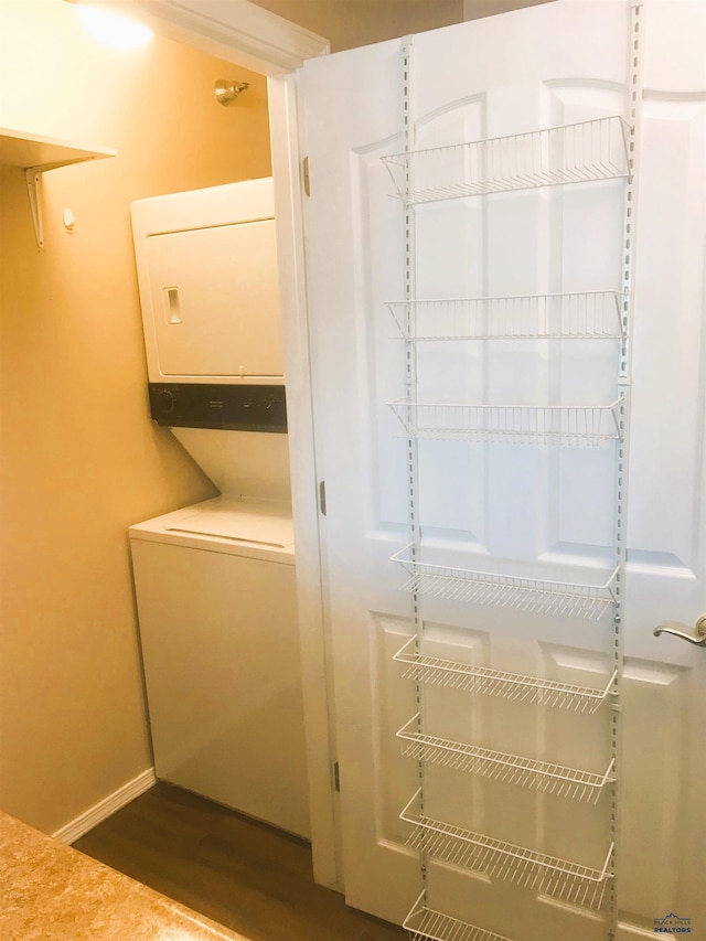 laundry area with stacked washer and dryer and dark hardwood / wood-style floors