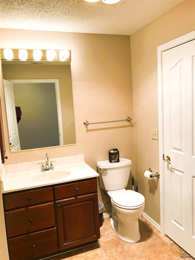 bathroom with tile patterned floors, vanity, toilet, and a textured ceiling