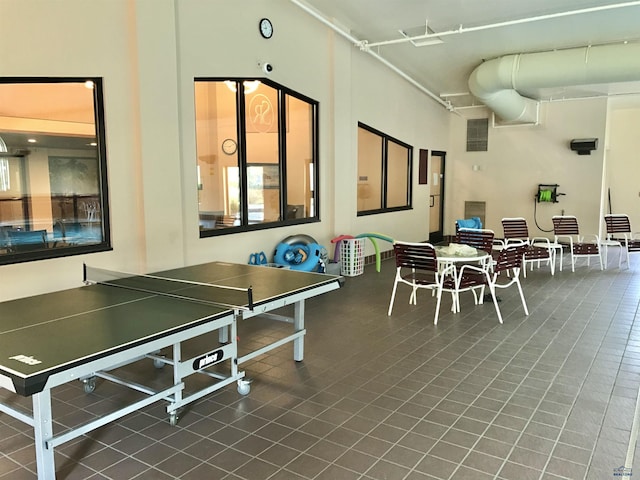 game room with tile patterned floors and a high ceiling