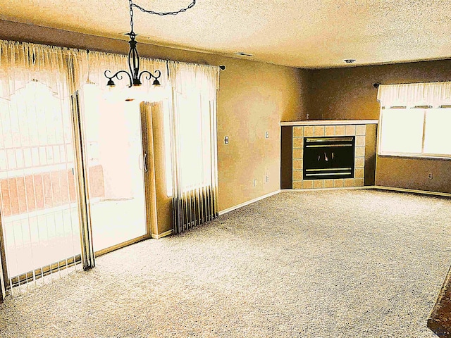 unfurnished living room with carpet flooring, a tile fireplace, and a textured ceiling