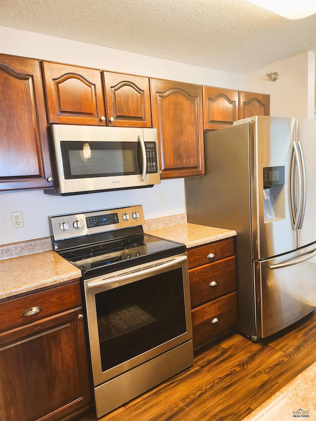 kitchen with dark wood-type flooring, appliances with stainless steel finishes, and a textured ceiling