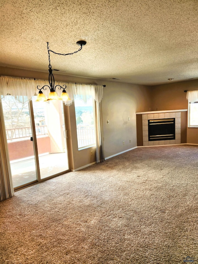 unfurnished living room featuring carpet, a textured ceiling, a notable chandelier, and a fireplace