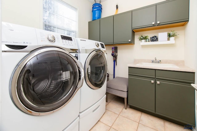 laundry area with cabinets, sink, light tile patterned floors, and washing machine and clothes dryer