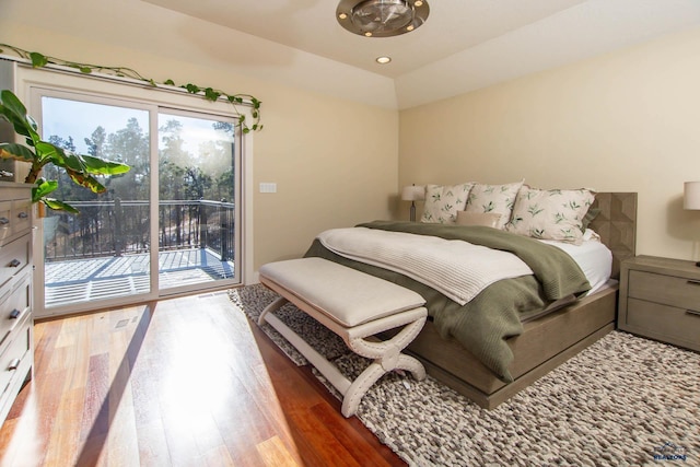 bedroom with wood-type flooring, vaulted ceiling, and access to outside