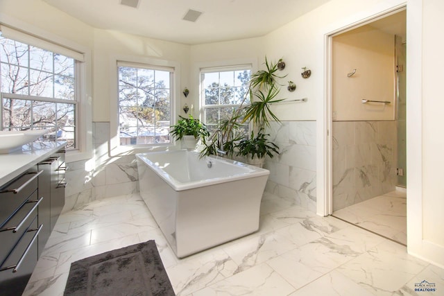 bathroom featuring vanity, tile walls, and a tub