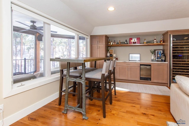 bar with ceiling fan, lofted ceiling, beverage cooler, and light wood-type flooring