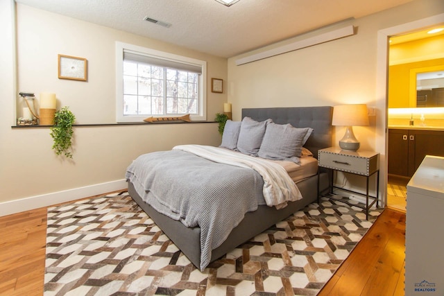 bedroom with light hardwood / wood-style floors and a textured ceiling