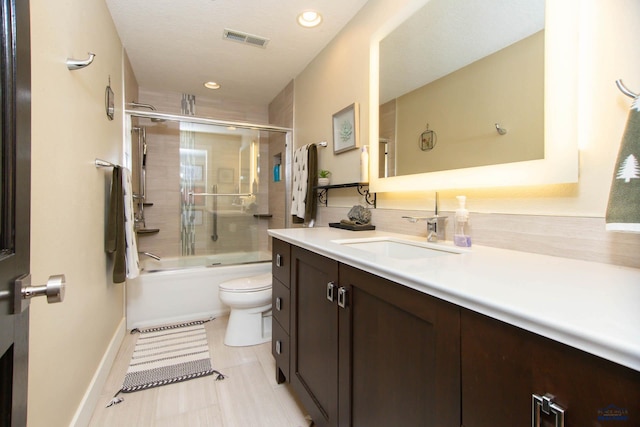 full bathroom featuring vanity, shower / bath combination with glass door, and toilet